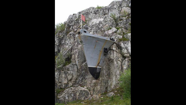 Russisches Kriegsschiff scheint in einem Steinberg in Murmansk, Russland, eingebettet zu sein